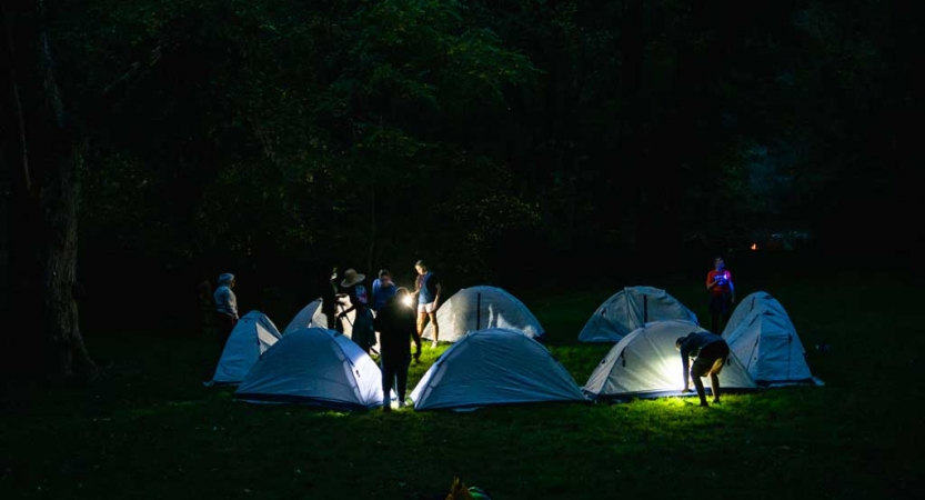 headlamps illuminate a campsite on an outward bound course